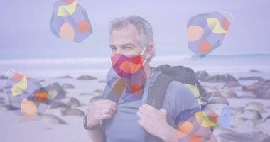 Sahilde sırt çantalı beyaz bir adamın portresine karşı hareket eden çok sayıda yüz maskesi. Coronavirus covid-19 salgın konsepti