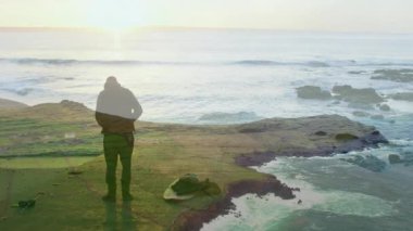 Kayalık sahilde duran kişi, arka plandaki okyanus dalgalarına karşı siluet oluşturdu. Kıyı şeridi, doğa, manzara, deniz manzarası, yalnızlık, sükunet