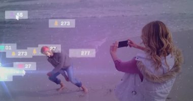 Plajda, insanlar animasyon örtülü sosyal medya bildirimleri alıyorlar. Teknoloji, iletişim, akıllı telefon, dijital bağlantı, deniz kenarı