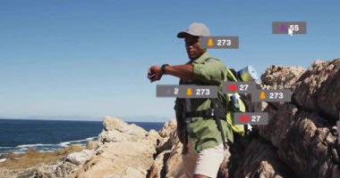 Kayalık sahillerde yürüyüş yapan, sosyal medya bildirimlerini izleyen bir adam. Macera, açık hava, kıyı şeridi, teknoloji, keşif, doğa