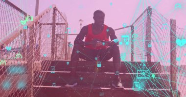 Dijital simgelerle dolu küreler merdivenlerde oturan Afro-Amerikan formda bir adama karşı. Spor, spor ve teknoloji konsepti