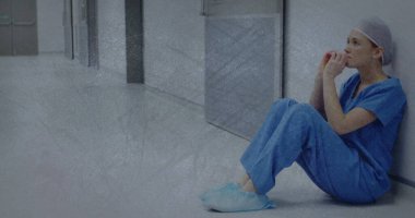 Hastanede oturan üzgün beyaz kadın hemşire üzerinde hareket eden şekiller. Uluslararası İşçilerin Anma Günü ve dijital olarak üretilen görüntü konsepti.
