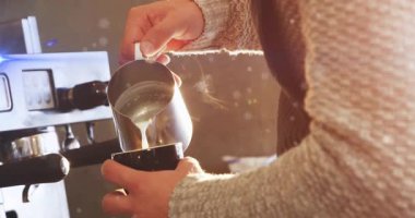 Barista 'nın metal sürahisinden bardağa 3 boyutlu olarak buğulanmış süt dökmesi, sıcak ışıklandırmayı vurguluyor. Kahve, profesyonellik, sanatçılık, ambiyans, sıcaklık, işçilik, konukseverlik.