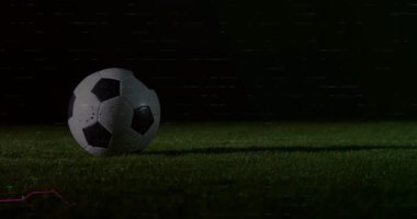 Futbol topu geceleri çim sahada dönüyor, dijital şamdan çizelgeleri ve moda çizgileri sergiliyor. Spor, analitik, görselleştirme, teknoloji, veri, açık hava, tek renk