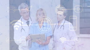 Doktorlar ve hemşire klinikteki tableti işaret ediyor. Yüzen ağ simgeleri teletıp olduğunu gösteriyor. Profesyonel, sağlık, dijital, bağlantı, takım çalışması, yenilik, teknoloji