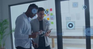 İş yerinde tablet üzerinde işbirliği yapan iki erkek iş arkadaşı yüzen veri tabloları sergiliyor. İşbirliği, yenilik, teknoloji, takım çalışması, modern, üretkenlik, veri görselleştirme