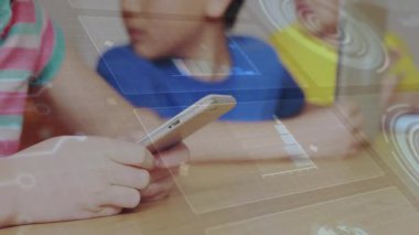Sınıfta telefon ve tablet kullanan üç öğrenci holografik çizelgeler ve ızgaralar sergiliyor. Teknoloji, eğitim, yenilik, işbirliği, dijital, gençlik, fütürizm