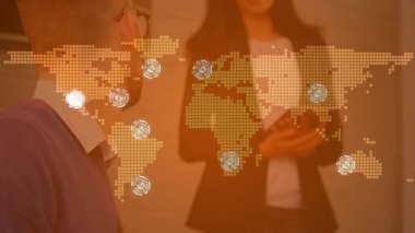 Erkek çalışan teknoloji ofisinde kadın konuşmacı dinliyor, dünya haritası takip düğümlerini örtüyor. Teknoloji, yenilik, işbirliği, dijital, iletişim, modern, profesyonel