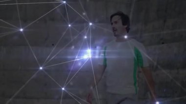 Duvara bakan raket tutan adam, spor teknolojisiyle parlayan ağ örtüsü sergiliyor. Atletik, yenilikçi, fütürist, ağ oluşturma, spor, dijital, teknoloji