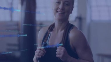 Spor salonunda ip atlayan bir kadın, spor salonu için yüzen dijital dalga formlarını gösteriyor. Fitness, determination, sport, technology, motivasyon, wellness, activewear