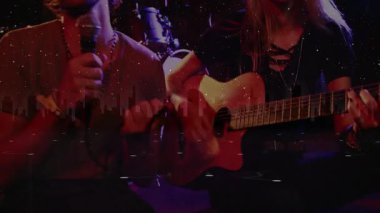 Sahne ışıkları altında müzik ikilisi sahne alıyor, mikrofon tutuyor ve yıldız parçacıklarıyla gitar tıngırdatıyor. Performans, konser, eğlence, bateri ustası, müzisyenler, canlı, sanatsal