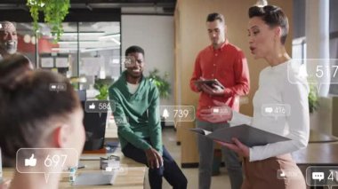 İş arkadaşları modern iş ofisindeki masanın etrafında toplanıp yüzen bildirim simgelerini gösteriyorlar. İşbirliği, takım çalışması, dijital iletişim, modern çalışma alanı, sosyal medya, canlı, dinamik