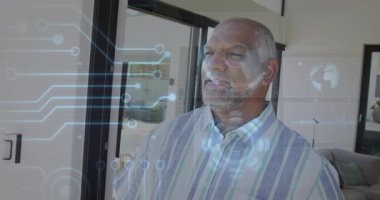Modern yaşam alanının içinde duran bir adam HUD grafikleri ve küresel ikon teknolojileri sergiliyor. Gelecek, teknoloji, yenilik, akıllı, dijital, bağlantı, modern