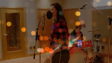 Vokalist, kayıt stüdyosunda canlı ses dalgalarıyla bateri çalarak mikrofon ve bateriste şarkı söylüyor. Stüdyo, performans, akustik, müzisyenler, kayıt, profesyonel, ses