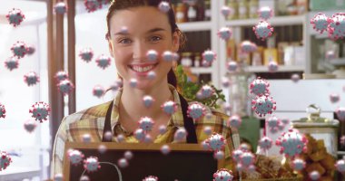 Kafe tezgahının arkasında yüzen koronavirüs simgeleriyle boş yazı tutan gülümseyen bir barista. Kahve dükkanı, fırın, konukseverlik, sıcak, davetkar, erdemli, köylü.