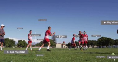 Futbol takımı spor teknolojisi çalışıyor, sahada AR uyarı kutularıyla top sürüyor. Atletizm, takım çalışması, yenilik, açık hava, rekabet, gençlik, modern