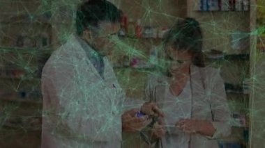 Yetişkin bir eczacı, eczanedeki müşteriye yeşil düğümlü ilaç kutusu gösteriyor. İlaç, sağlık, danışma, dijital, profesyonel, ilaç, sağlık