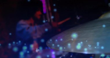 Erkek davulcu canlı müzik sahnesinde canlı müzik çubukları sallıyor, renkli bokeh hareketleriyle. Perküsyon, canlı, dinamik, sanatsal, gece hayatı, eğlence, soyut