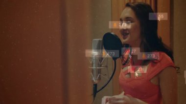 Kadın kayıt stüdyosunda müzik içeriği yaratıyor, yüzen sosyal medya nişan ikonlarıyla. Vokalist, etkili, kayıt, ses geçirmez, dijital, multimedya, yaratıcı