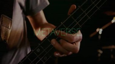 Müzik teknolojisi stüdyosunda bas gitar çalan erkek müzisyen yeşil METAVERSE kaplamasını sergiliyor. Müzisyen, enstrüman, dijital, fütüristik, ambians, yaratıcılık, performans