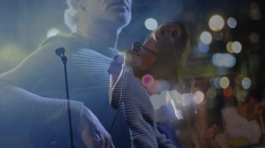 Erkek ve kadın şarkıcı mikrofon tutarak iki kez sahne alarak konser veriyor. Performans, konser, eğlence, sahne, gece hayatı, müzikal, sanatçılık