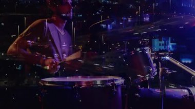 Mor ışıklar altında davul çalan erkek davulcu, şehir ışık yollarını, müzik grafiklerini örtüyor. Müzik, performans, gece hayatı, şehir, atmosfer, enerji, ritim