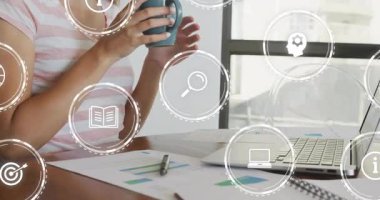 Modern ofis çalışma alanında, yüzen iş veri analiz simgeleriyle kupadan yudumlayan bir kadın. Üretkenlik, yenilik, teknoloji, gündelik, çağdaş, çalışma alanı, yaratıcı