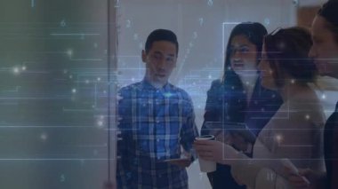 Cam duvarın etrafında iş birliği yapan dört kişilik bir iş ekibi haritaları ve şebeke şemalarını analiz ediyor. İşbirliği, yenilik, teknoloji, beyin fırtınası, modernlik, takım çalışması, veri görselleştirme