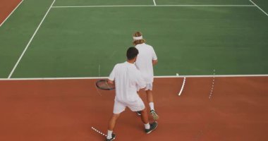 Erkek tenis partnerleri sahada hareketli spor teknolojisi çizelgeleriyle yürüyorlar. Atletik, rekabet, spor, takım çalışması, canlı, enerjik, boş zaman
