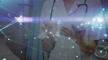 Kadın doktor tıbbi tesiste tablet tıkırdatıyor, parlayan ağ hatları ve düğümleri gösteriyor. Tıbbi, sağlık, teknoloji, yenilik, profesyonel, modern, tanı