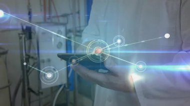 Fabrikada tablet tutan erkek teknisyen, parlayan ağ düğümlerini ve bağlantı hatlarını gösteriyor. Sanayi, teknoloji, yenilik, otomasyon, mühendislik, makine, bağlantı