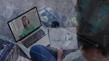 Evde bağdaş kurmuş bir adam uzaktan iş görüşmesine katılıyor ve animasyon bar çizelgeleri gösteriyor. İşbirliği, uzaktan çalışma, dijital görselleştirme, ev ofisi, profesyonel, yaratıcı, çağdaş