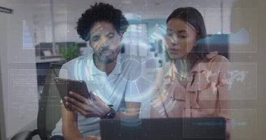 Modern ofiste teknoloji projesinde işbirliği yapan meslektaşlar, tablet dizüstü bilgisayarları HUD çizelgeleriyle gösteriyorlar. Teknoloji, takım çalışması, yenilik, dijital, modern, çalışma alanı, veri