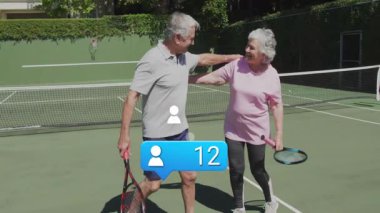 Tenis kortunda kol kola yürüyen yaşlı çift, yüzen sağlık verileri grafikleri gösteriyor. Açık hava, fitness, boş zaman, atletik, canlılık, uyum, yaşam tarzı