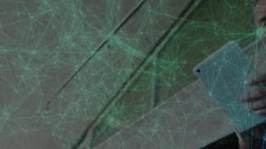 Kapalı alandaki tabletle etkileşime giren bir adam, teknolojik görseller için canlı yeşil ağ düğümleri sergiliyor. Teknoloji, yenilik, bağlantı, fütürizm, profesyonellik, modern tasarım, veri görselleştirme