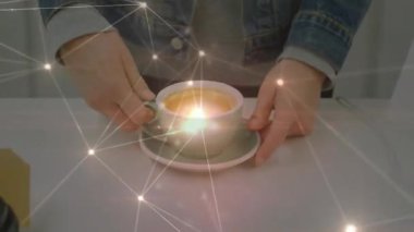 Eller kahve fincanının yanında dinleniyor, kapsüller teknoloji için dijital ağ örtüsünü gösteriyor. Minimalist, çağdaş, fütürist, üretkenlik, bağlantı, yenilik, çalışma alanı