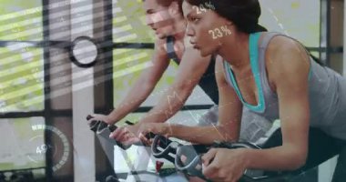Spor salonunda bisiklet süren arkadaşlar animasyon performans ölçümleri ve şematik grafikler sergiliyorlar. Fitness, yoldaşlık, motivasyon, kardiyo, yenilik, canlılık, açık hava