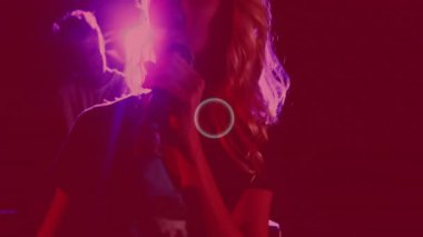 Kadın elinde mikrofon, gece kulübünde müzik tanıtımı, ekolayzır barlar ve neon patikalar var. Gece hayatı, konser, sahne, enerji, kutlama, kentsel, canlı