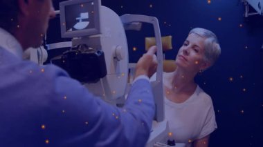 Kadın hasta, optometri odasında yüzen turuncu ışıklarla çene yerleştiriyor. Tıbbi, sağlık, tanı, teknoloji, profesyonel, klinik, ekipman