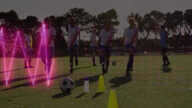 Futbol takımı çim sahada kameraya doğru yürüyor. Neon HR grafikleri koni ve top üzerinde. Atletik, takım çalışması, spor giyim, antrenman, spor, spor, canlı, açık hava.