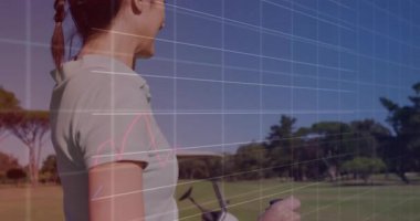 Olgun bayan golfçü, saha kenarında yüzen teknik çizelgeleriyle performansı takip ediyor. Atletik, analitik, fitness, açık hava, teknoloji, performans, strateji