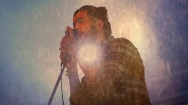 Sis bulutunun arkasında duran adam, animasyon parçacıklarıyla müzik sahnesi ortamını sergiliyor. Çevresel, ruhani, atmosferik, soyut, konser, performans, canlı
