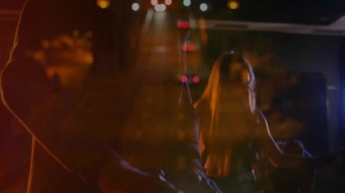 Orkestra arkadaşları sahne ışıkları altında klavye çalıyor, mikrofonu yüzen teknoloji simgeleriyle kullanıyorlar. Canlı performans, gece hayatı, sahne aydınlatma, müzik topluluğu, kentsel, sanatsal, canlı