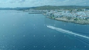 Sürat teknesi derin mavi denizi kesiyor, beyaz iz bırakıyor, beyaz sahil binalarını ortaya çıkarıyor. Sahil, deniz, manzara, macera, coşku, dinginlik, denizcilik