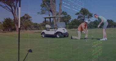 Erkek golfçü diz çöküp golf arabasının yanına yeşil giyip, finans grafiklerini sergiliyor. Lüks, boş zaman, açık hava, spor, zarafet, takım çalışması, doğa.