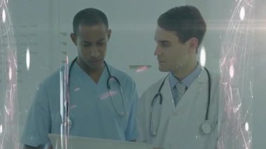 Hastane koridorunda dizüstü bilgisayarı inceleyen iki erkek doktor ve dijital ağ örtüsü. Tıp uzmanları, işbirliği, yenilik, sağlık, modern, teknoloji, takım çalışması