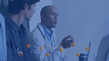 Doktorlar laptopta klinik verileri tartışıyor, sağlık sektöründe yüzen emoji simgelerini sergiliyorlar. Tıbbi ekip, işbirliği, modern sağlık, profesyonel çevre, dijital teknoloji, klinik tartışma, yenilik