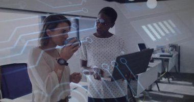 İki kadın çalışan ofiste iş verilerini analiz ediyor, dizüstü bilgisayarlarını holografik çizelgelerle kaplıyorlar. İşbirliği, yenilik, teknoloji, üretkenlik, fütürizm, işyeri, dijital