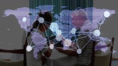 Kıdemli adam ve bakıcı harita simgeleriyle yemek masasında dijital iletişimi inceliyor. Teknoloji, iletişim, bağlantı, dijital, nesiller arası, yenilik, ev