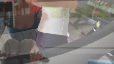 Kadın spor salonunda koşu bandında koşuyor, konsolun üzerinde hareketli fitness ölçümleri var. Fitness, egzersiz, kardiyo, sağlık, motivasyon, canlılık, eğitim